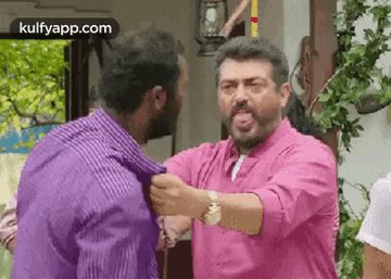 a man in a pink shirt is fighting another man in a purple shirt in a room .