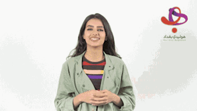 a woman in a green jacket is smiling in front of a white background with arabic writing
