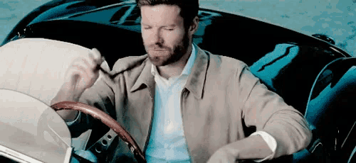 a man in a tan jacket is sitting in a black car