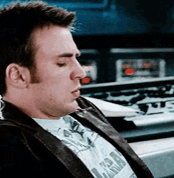 a man wearing a leather jacket and a t-shirt that says ' captain america ' on it is sleeping