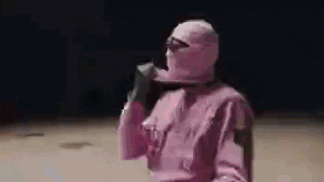 a person wearing a pink ski mask is holding a gun .