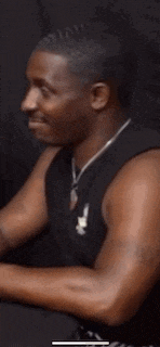 a man wearing a black tank top and a necklace is smiling .