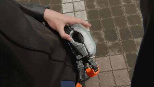 a person is holding a toy that looks like a robot on a brick walkway