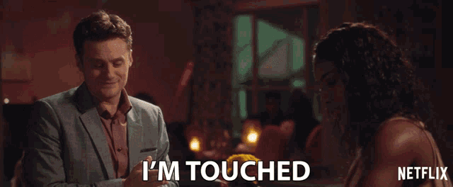 a man in a suit says i 'm touched next to a woman