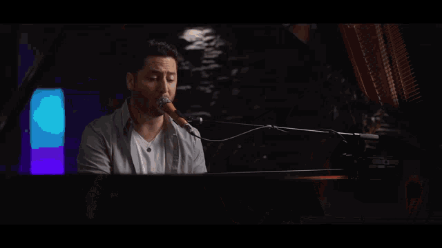 a man is playing a piano and singing into a microphone