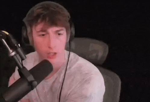 a young man is wearing headphones and talking into a microphone .