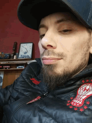 a man with a beard wearing a hat and a jacket with a patch that says ' nba ' on it