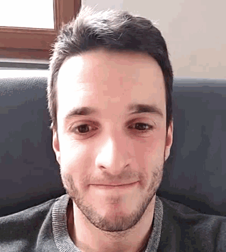 a man with a beard is smiling and wearing a grey shirt