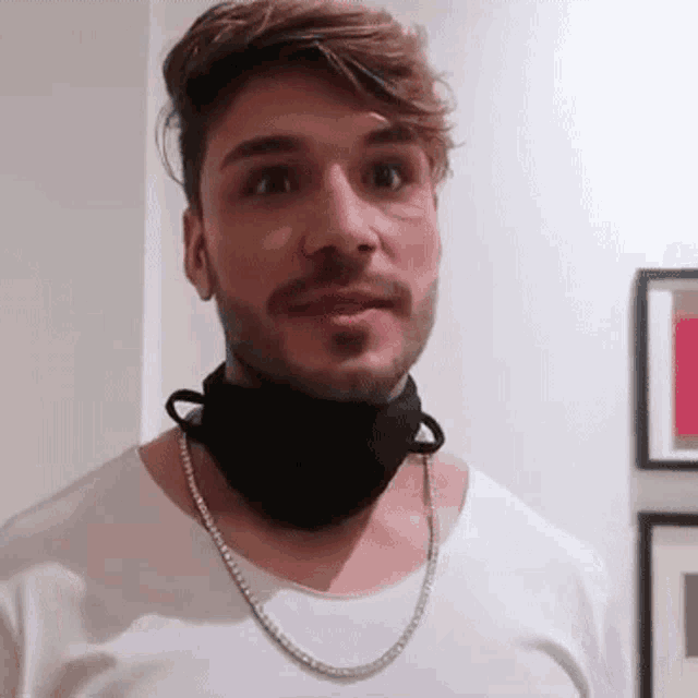 a man with a beard is wearing a black mask around his neck and a chain around his neck .
