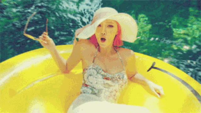 a woman wearing a hat and sunglasses sits in a yellow raft in the water