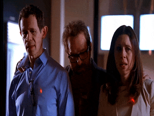 a man in a blue shirt has a red light on his shirt pocket
