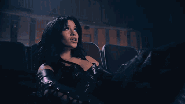 a woman in a black corset is sitting in a dark auditorium