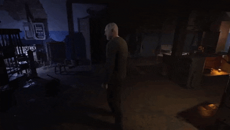 a man is standing in a dark room in a video game looking at something .