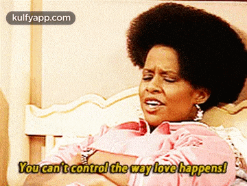 a woman in a pink dress is sitting on a bed and says you can 't control the way love happens