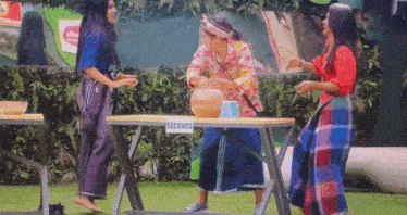 three women standing around a table that says seconds on it