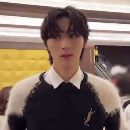 a young man wearing a black and white sweater and a white shirt is standing in a room .