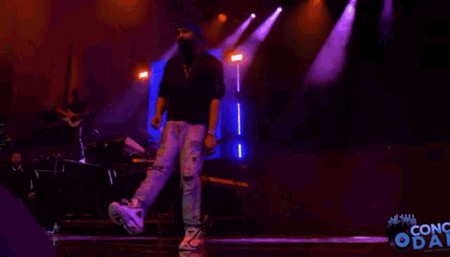 a man dancing on a stage with a sign that says conc oda