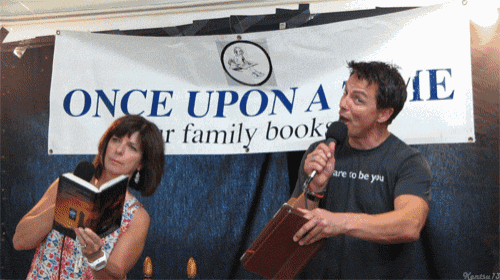 a man and a woman are standing in front of a sign that says once upon a time
