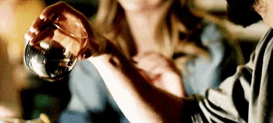 a woman is holding a bottle of perfume in front of her chest .