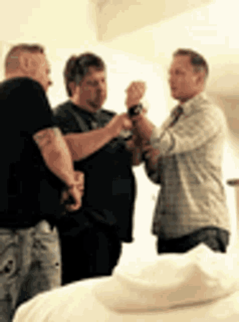 three men are standing next to each other in a room with a bed .