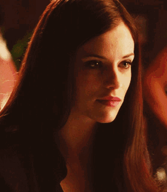a woman with long dark hair and pink lips looks at the camera