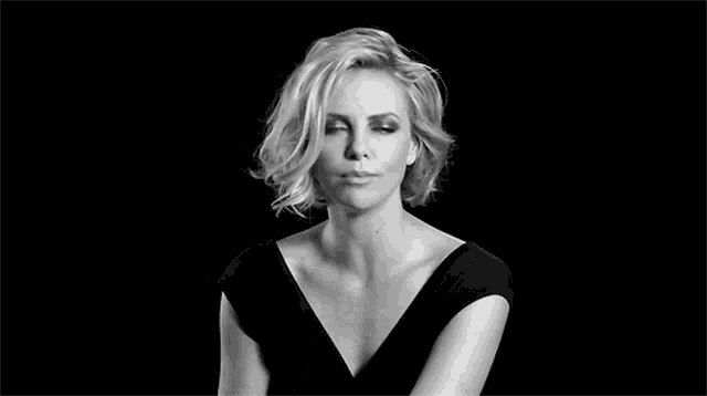 a black and white photo of a woman in a black dress making a face .