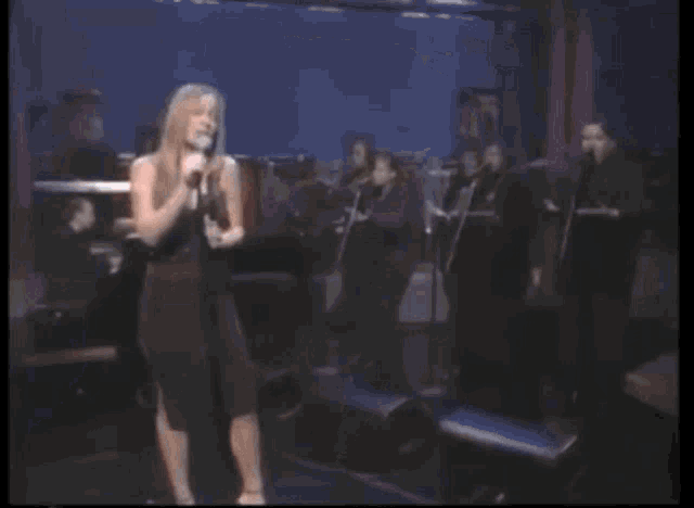 a woman singing into a microphone in front of a piano
