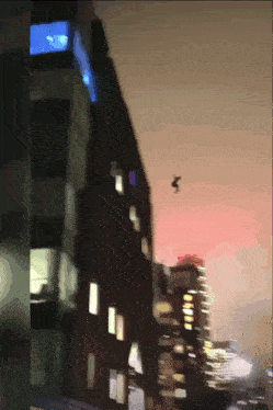 a person is flying through the air near a building at night