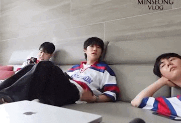 three young men are sitting on a couch with their feet up .