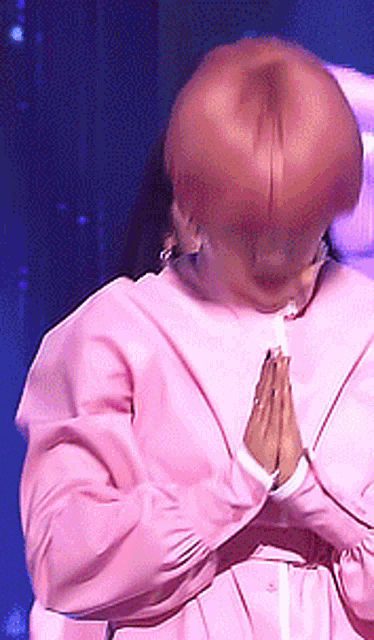 a woman in a pink dress is praying with her hands folded in front of her face