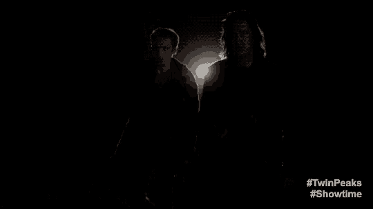 two men are standing next to each other in the dark and looking at the camera .