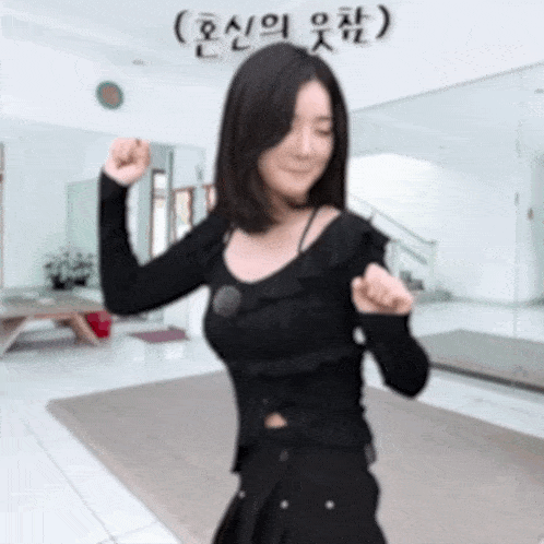 a woman in a black top is flexing her muscles in front of a mirror in a room