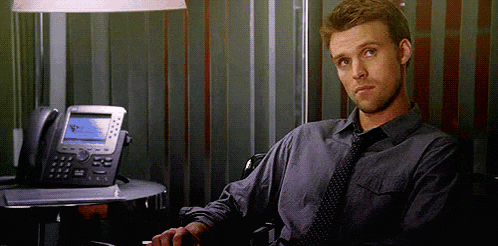 a man in a tie is sitting in front of a desk with a telephone .