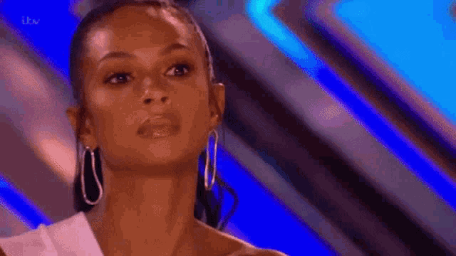 a woman wearing hoop earrings is smiling and looking at the camera .