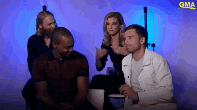 a group of people are sitting in front of a blue background with the gma logo on it