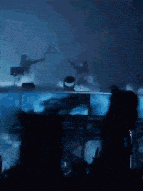 a group of people are dancing in a dark room with a blue background
