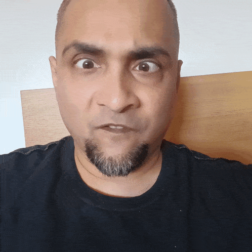 a man with a beard and a black shirt makes a surprised face