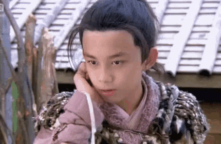 a young boy is talking on a cell phone while wearing a traditional costume .