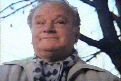an older man wearing a scarf and a jacket looks up at the sky