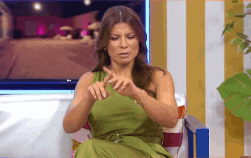 a woman in a green dress is sitting in front of a television