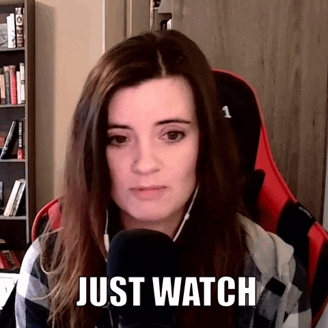 a woman is sitting in front of a microphone with the words just watch above her head .