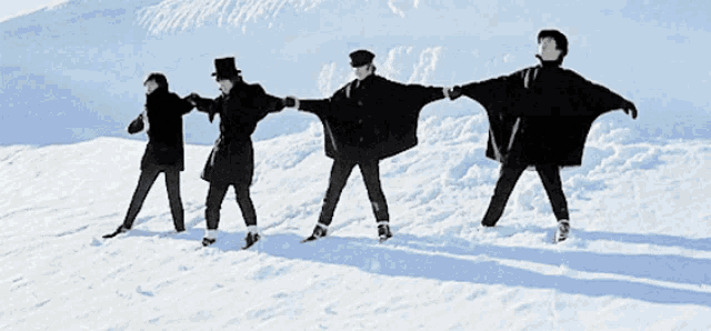 four people standing in the snow holding hands