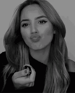 a woman is blowing a kiss in a black and white photo while holding a remote control .