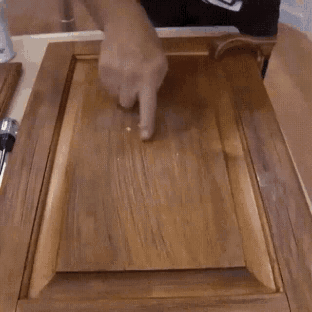 a person is pointing to a piece of wood