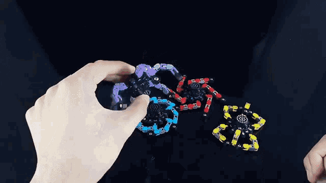 a person is playing with a fidget spinner in their hands against a black background .