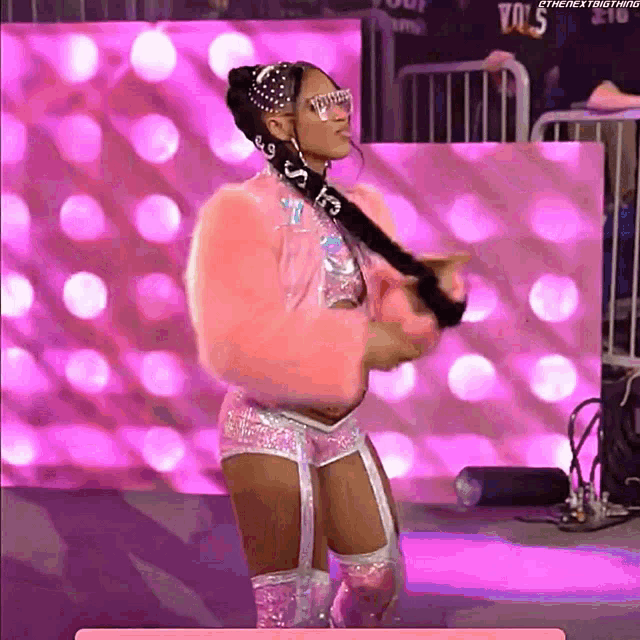 a female wrestler is wearing a pink fur coat and shorts with the letters ks on them