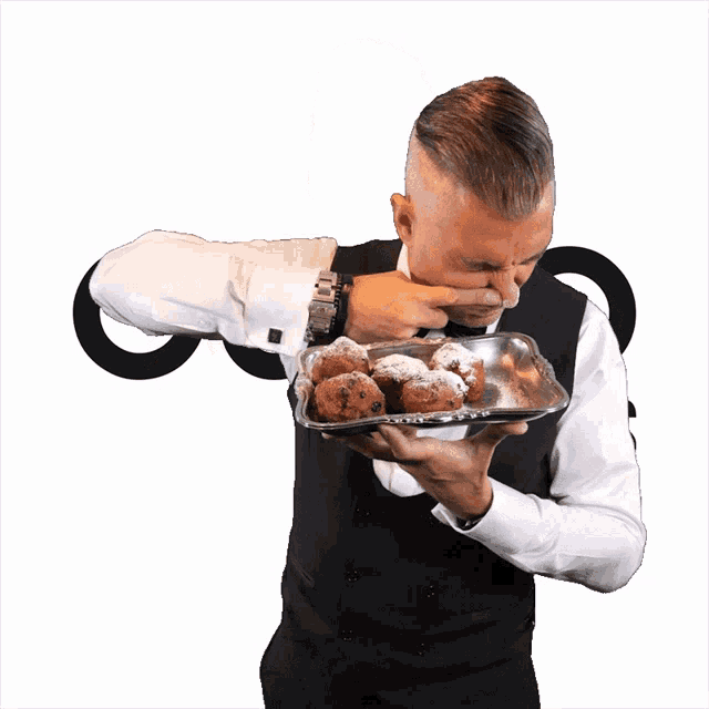 a man in a tuxedo is holding a tray of donuts