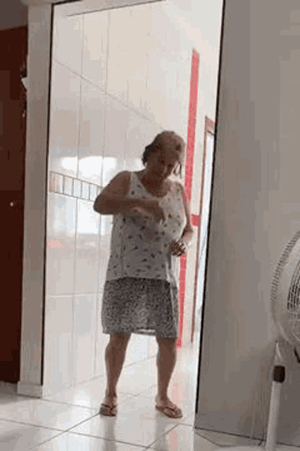 a woman is dancing in a hallway in front of a fan .