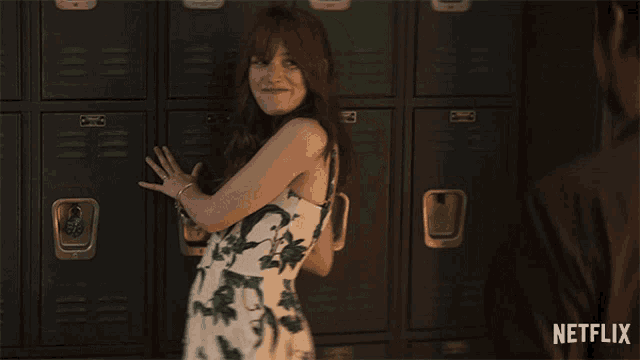 a woman standing in front of a row of black lockers with a netflix logo on the bottom