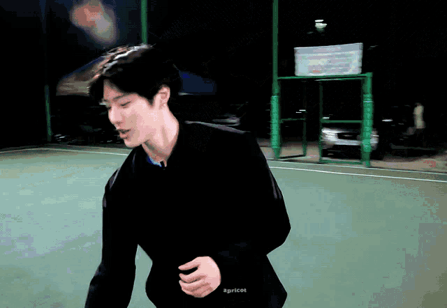 a man in a black jacket is holding a soccer ball on a soccer field